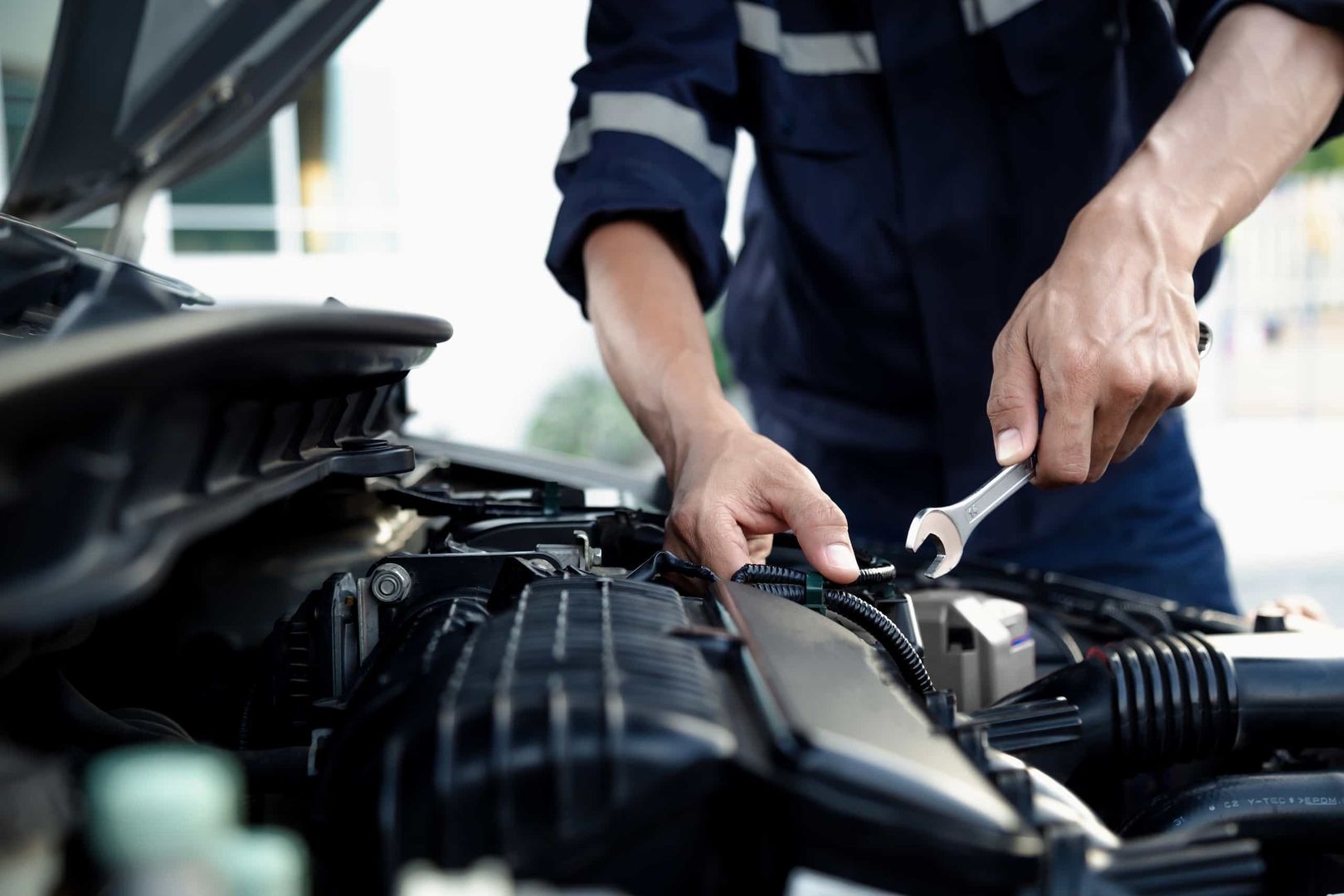 Ein Mann arbeitet an einem Motor eines Autos und führt Reparaturen durch.